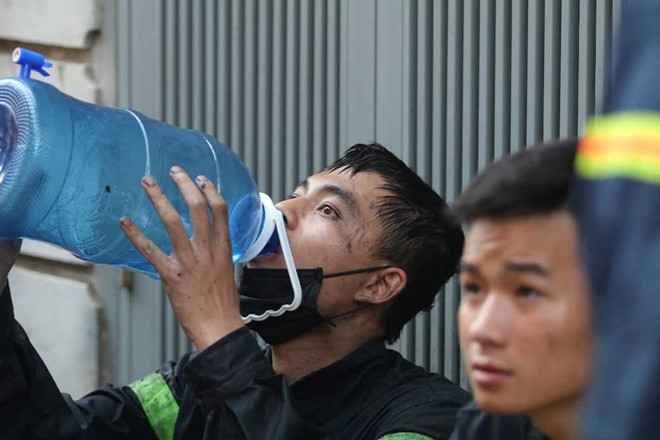 Một chiến sĩ cảnh sát uống nước trong ít phút nghỉ để có sức tiếp tục nhiệm vụ. (Ảnh: CAND).