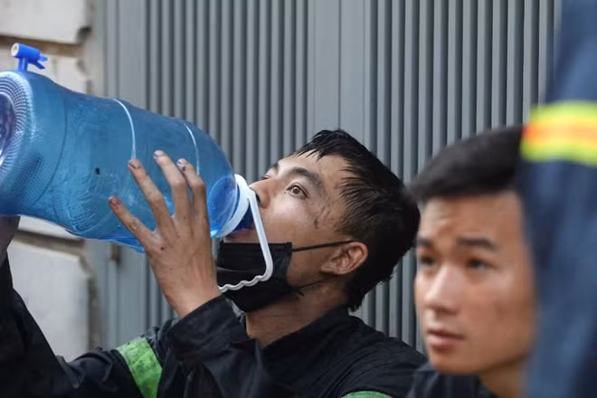 Một chiến sĩ cảnh sát uống nước trong ít phút nghỉ để có sức tiếp tục nhiệm vụ. (Ảnh: CAND).