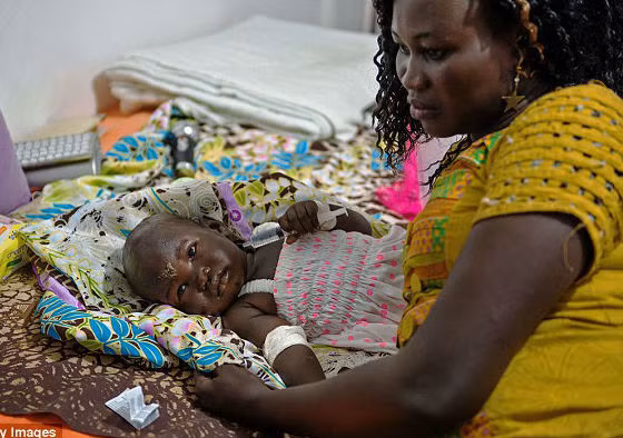 Bé Nyalou Thong, 13 tháng tuổi, là một trong hai người duy nhất may mắn sống sót trong vụ máy bay rơi tại Nam Sudan ngày 4/11. Ảnh: Bé Nyalou đang nằm trên giường bệnh, bên cạnh là phóng viên Achol Deng.