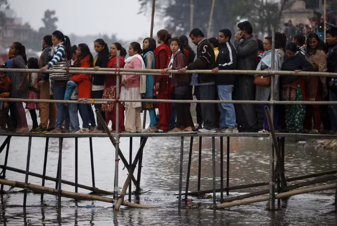 Các tín đồ xếp hàng đi qua cây cầu tạm bợ để tới sông Bagmati ở Kathmandu, Nepal.