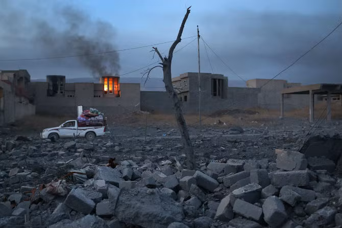 Người dân vận chuyển đồ đạc qua một khu vực đổ nát.