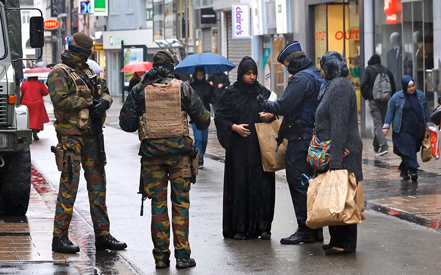 Binh sĩ và cảnh sát Bỉ kiểm tra giấy tờ của một người phụ nữ trên đường phố Brussels.