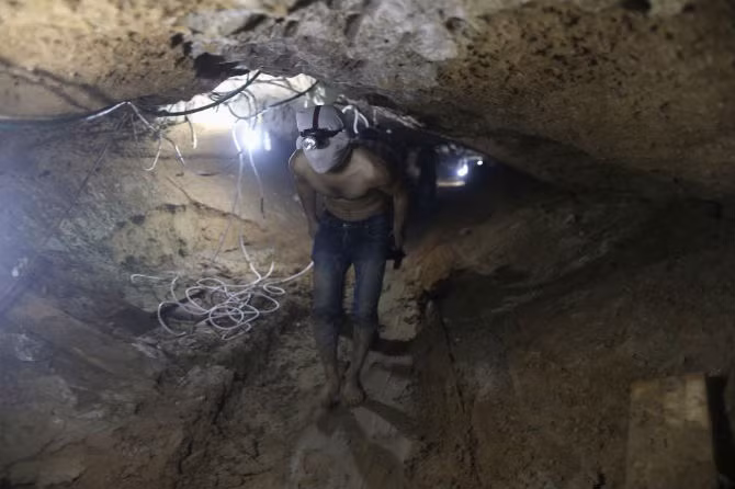 Sau đó, nước này nhiều lần bơm nước nhằm phá hủy hệ thống hầm ngầm. Ảnh: Một công nhân Palestine trùm kín mặt đi bộ trong đường hầm.