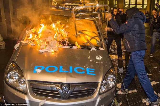Một chiếc xe của cảnh sát Anh bị đập phá, đốt cháy.
