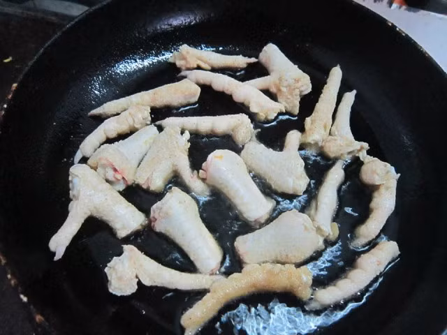 Bước 2: Bắc chảo lên bếp, đổ dầu vào chảo đun sôi rồi chiên giòn chân gà.