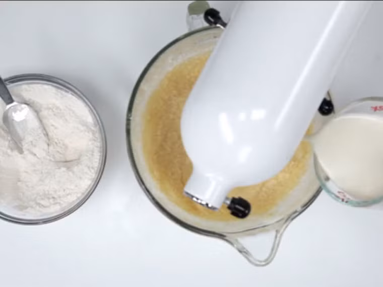 Đợi đến khi bột nhuyễn, cho thêm tinh dầu chuối, baking soda, bột nở, muối trộn lại.