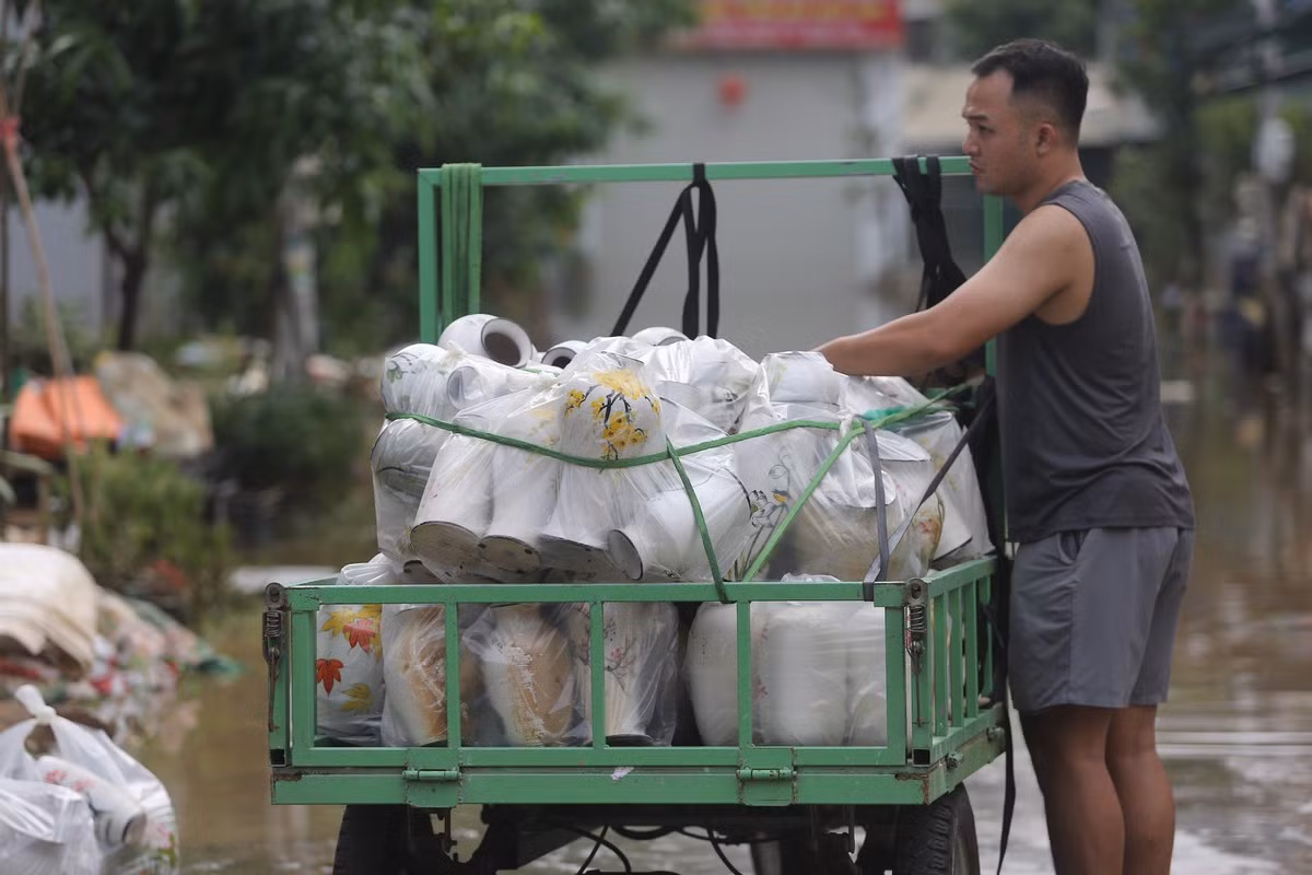 Người dân vận chuyển sản phẩm gốm ra khỏi vùng ngập úng.