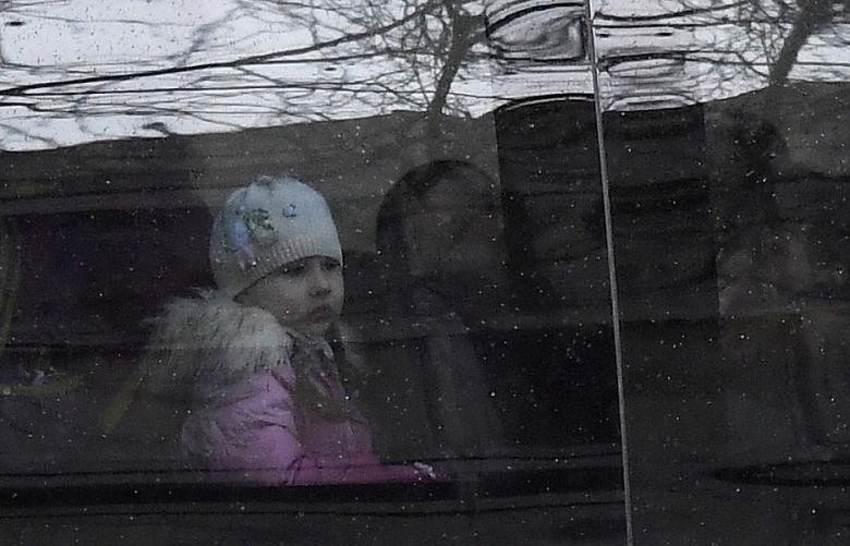 Một em nhỏ nhìn ra ngoài cửa sổ khi ngồi trên xe buýt.