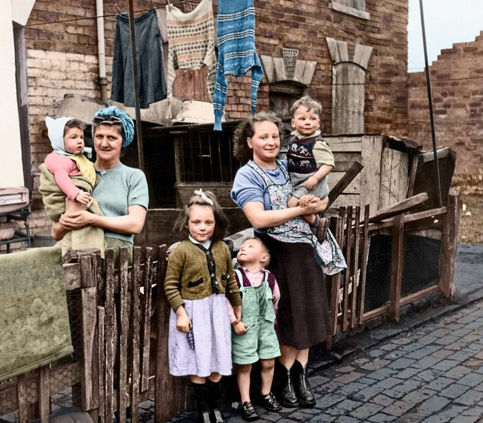 Hai người phụ nữ cùng con cái họ đứng trước ngôi nhà chật chội ở Birmingham ngày 6/2/1954.