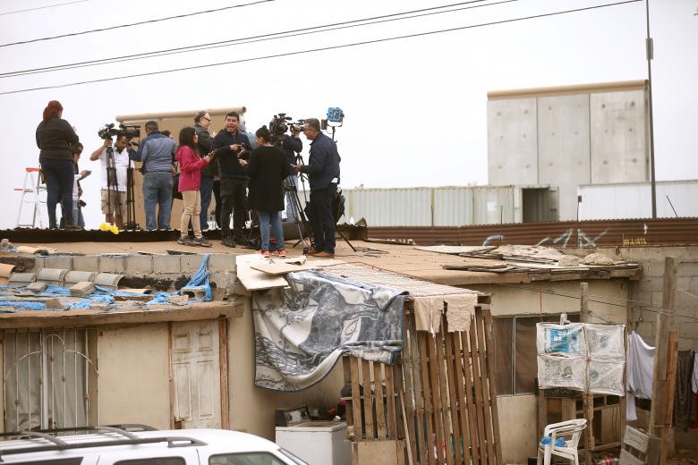 Các phóng viên đứng trên mái nhà cạnh hàng rào biên giới hiện tại ở Tijuana, Mexico, trong chuyến thị sát của ông Trump.