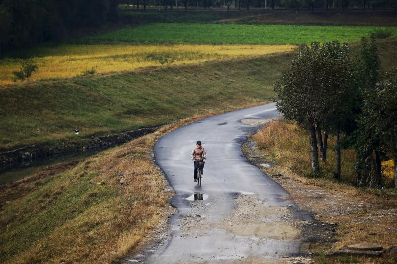 Người phụ nữ đi xe đạp trên con đường ở ngoại ô Bình Nhưỡng ngày 11/10/2015.