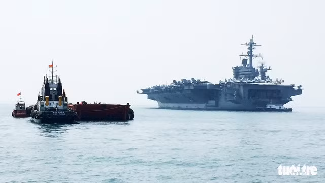 Tàu kéo di chuyển sà lan về phía cuối tàu sân bay USS Carl Vinson - Ảnh: THÁI BÁ DŨNG
