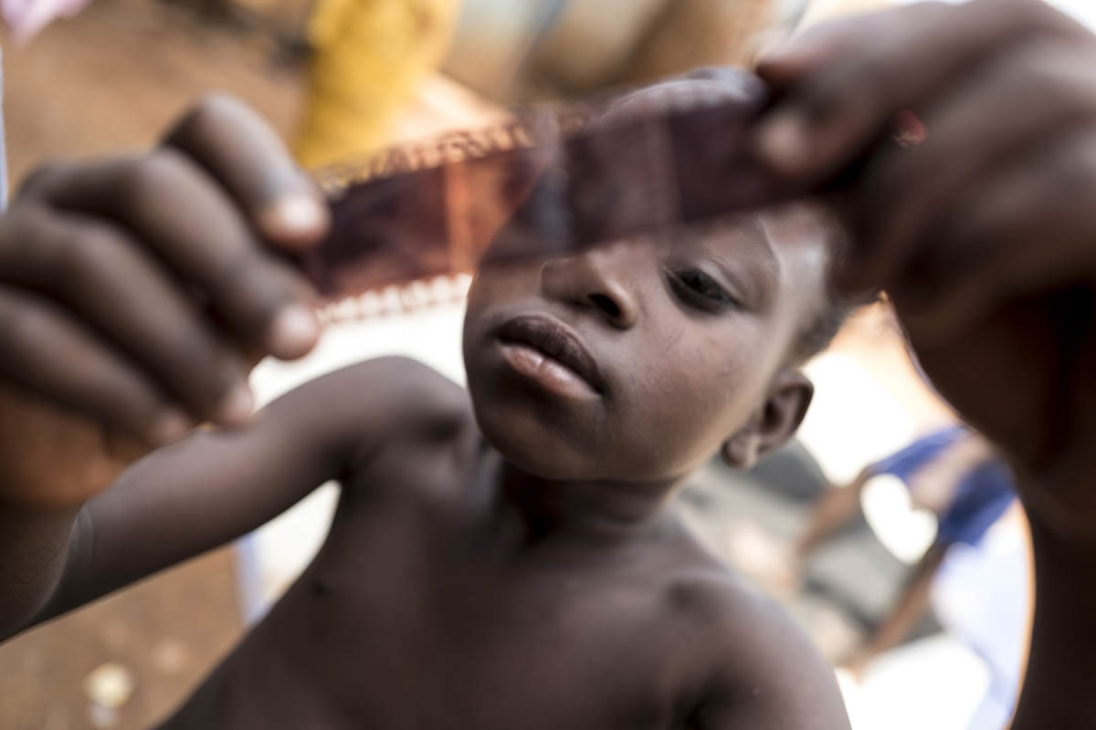 Isaac Newton, cậu con trai 9 tuổi của Nabwana, đang xem một cuộn phim âm bản của cha mình.