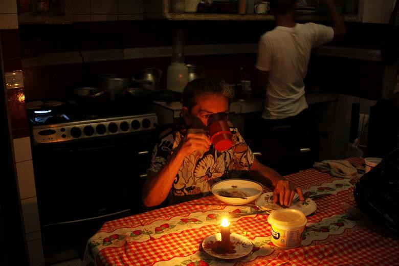 Đa số các gia đình phải sử dụng nến để thắp sáng. Ảnh: Juana Guerrero ngồi ăn dưới ánh nến trong nhà ở San Cristobal ngày 13/3. Ảnh: Reuters.
