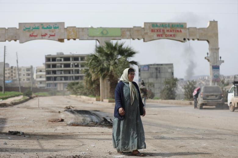Người phụ nữ đi bộ gần một chốt kiểm soát của FSA ở Afrin, Syria, ngày 18/3. Ảnh: Reuters.