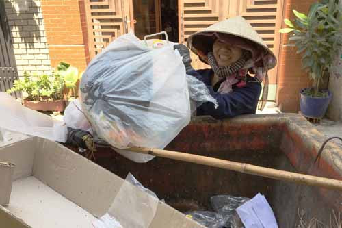 Chị Phượng đang gom rác, miệng luôn nở nụ cười.