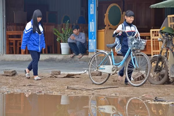 Các em học sinh không dám đi qua mà phải dắt bộ ở rìa đường.
