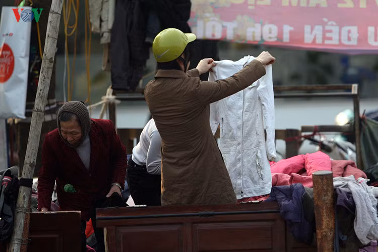 Một bạn trẻ đang ngắm nghía chiếc áo khoác nhàu nát mới bởi được trong đống đồ ngổn ngang. Ở đây, những món đồ được bán lẫn lộn cả cũ và mới, với giá chỉ từ vài chục ngàn đồng đến 1-200 ngàn.