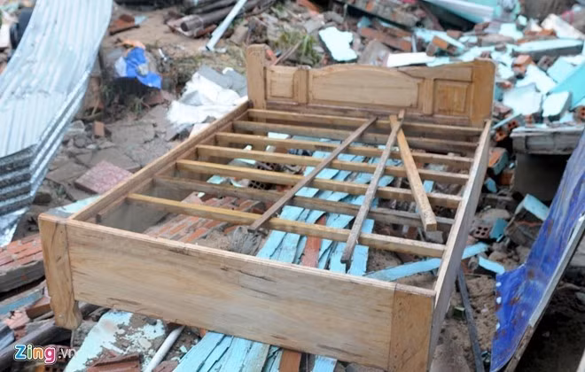 Giường cưới mới đóng dành cho đôi vợ chồng trẻ nằm chỏng chơ trên nền gạch đổ nát của căn nhà.