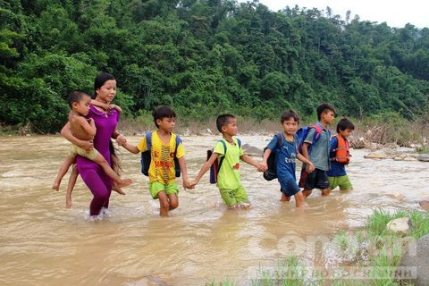 Các giáo viên “cắm bản” ở bản Vịn (thuộc xã Yên Thắng, huyện miền núi Lang Chánh, tỉnh Thanh Hóa) lội nước, cõng học trò qua sông đến trường. Nguồn ảnh: Công an TP HCM.