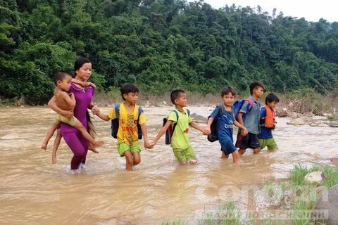 Các giáo viên “cắm bản” ở bản Vịn (thuộc xã Yên Thắng, huyện miền núi Lang Chánh, tỉnh Thanh Hóa) lội nước, cõng học trò qua sông đến trường. Nguồn ảnh: Công an TP HCM.