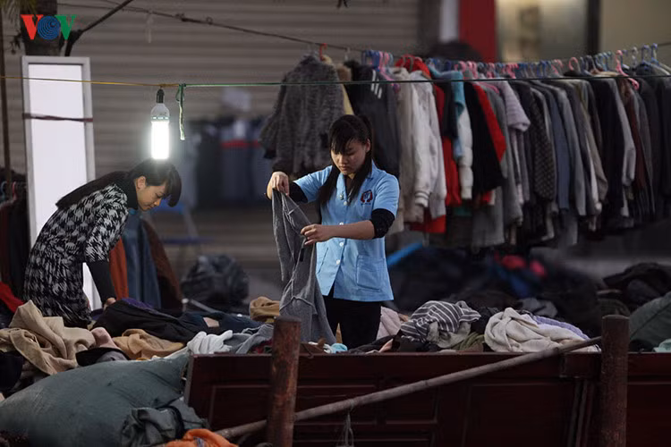 2 nữ công nhân trẻ đang chăm chú chọn những chiếc áo rét cho mùa đông sắp tới.