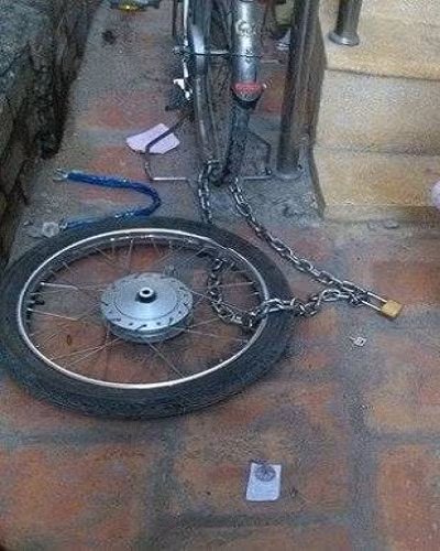 Một tên trộm đối phó với khóa chống trộm của khổ chủ, nẫng xe để lại bánh.