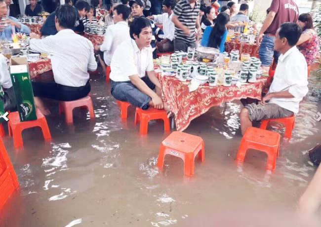 Đám cưới mùa lũ có những khó khăn, vất vả song hơn hết, cô dâu chú rể và họ hàng, người thân vẫn rất vui vẻ trong ngày đại hỉ. Mới đây, hình ảnh một đám cưới đã diễn ra trong thời tiết mưa lũ ở Khánh Hòa khiến nhiều người quan tâm. Khách đến tiệc cưới xắn quần ngồi ghế nhựa ăn tiệc.
