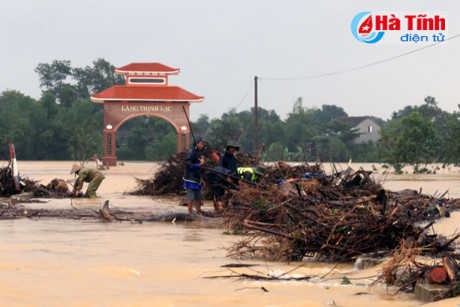 Mặc dù đã được chính quyền cảnh báo nguy hiểm song người dân vẫn bơi thuyền ra giữa dòng nước lũ, hay đứng trên cầu tràn, nước chảy xiết để vớt củi. Nguồn ảnh: Hà Tĩnh điện tử.