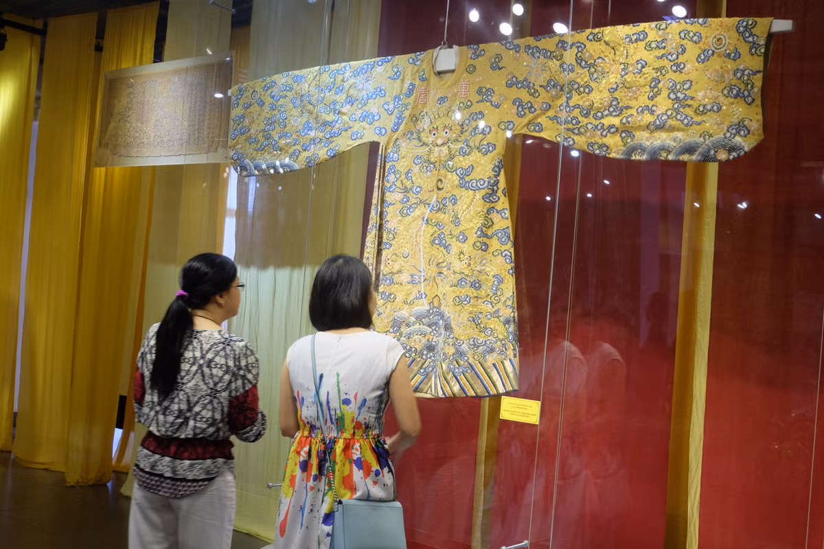 Theo chia sẻ của nghệ nhân Vũ Giỏi, các bộ trang phục này được nghiên cứu, phục dựng trong suốt 30 năm làm nghề. Hình ảnh khách tham quan thích thú ngắm bộ long bào của vua Bảo Đại được phục dựng.