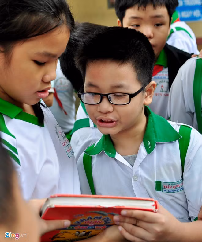 Cậu bé dịch cuốn sách giúp bạn ở trường Tiểu học Trần Quốc Tuấn.
