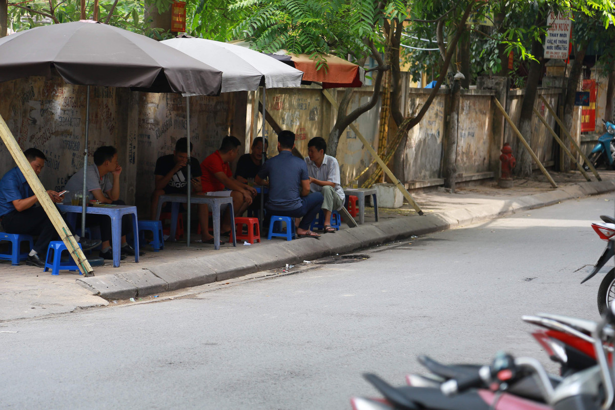 Cả người bán nước và khách đang coi thường tính mạng của bản thân khi ngồi dưới bức tường sắp đổ.