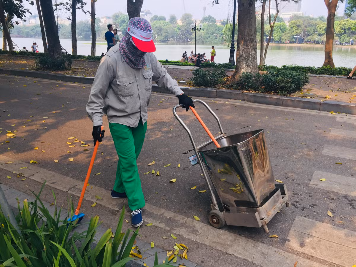 16h khi cái cũng dịu nhẹ phần nào nhưng khăn khố, áo dài bảo hộ, gang tay cũng được cô lao công ở phố Hàng Trống - Hà Nội che kín mít người. Cô bảo: “Mình ở đội U1 cơ, nay được điều sang đây hỗ trợ vì tháng này lá rụng nhiều mới nhiều sự kiện nữa”. 