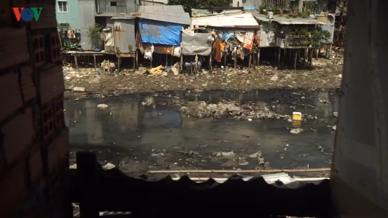 Rác thải trôi nổi ngay sát những ngôi nhà tạm bợ, lụp xụp ven sông.