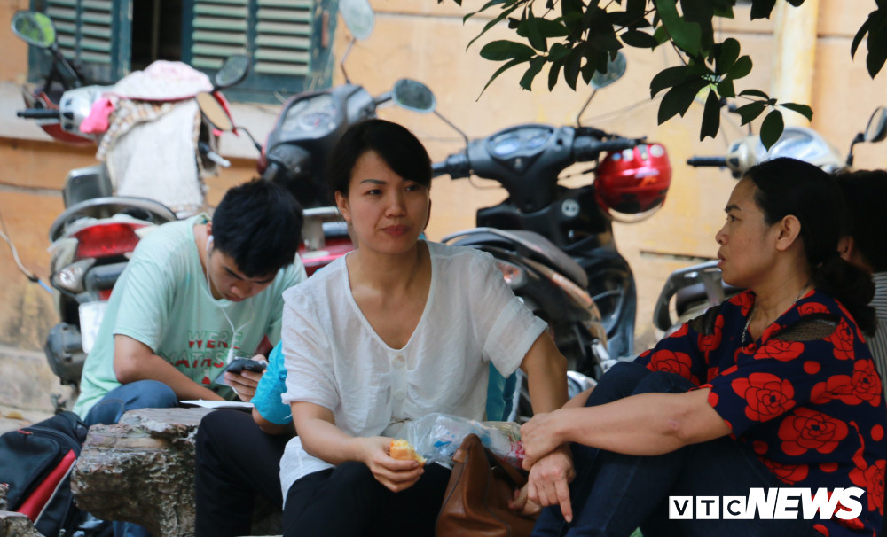 Trong lúc chờ đợi, một phụ huynh tranh thủ ăn sáng. Khuôn mặt lộ rõ sự lo lắng.