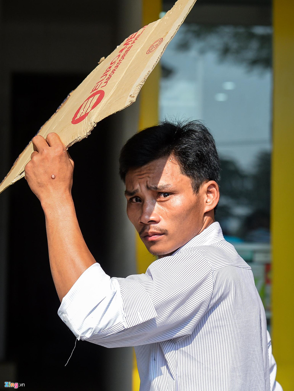 Anh Nguyễn Văn Tuấn sau khi ngồi uống trà đá đã xin tấm bìa carton để che nắng trong khi đi bộ ra bến xe buýt.