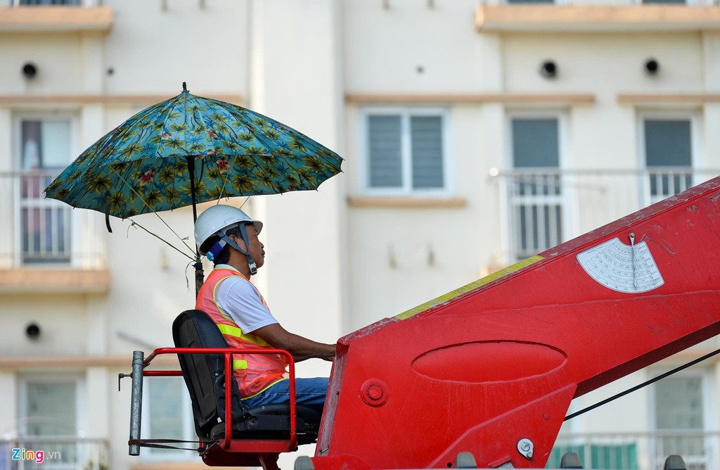 Công nhân lái cần cẩu trên đường Trường Chinh buộc một cái ô để tạo bóng mát. Do khu vực làm việc toàn bê tông, cái nóng càng trở nên hầm hập.