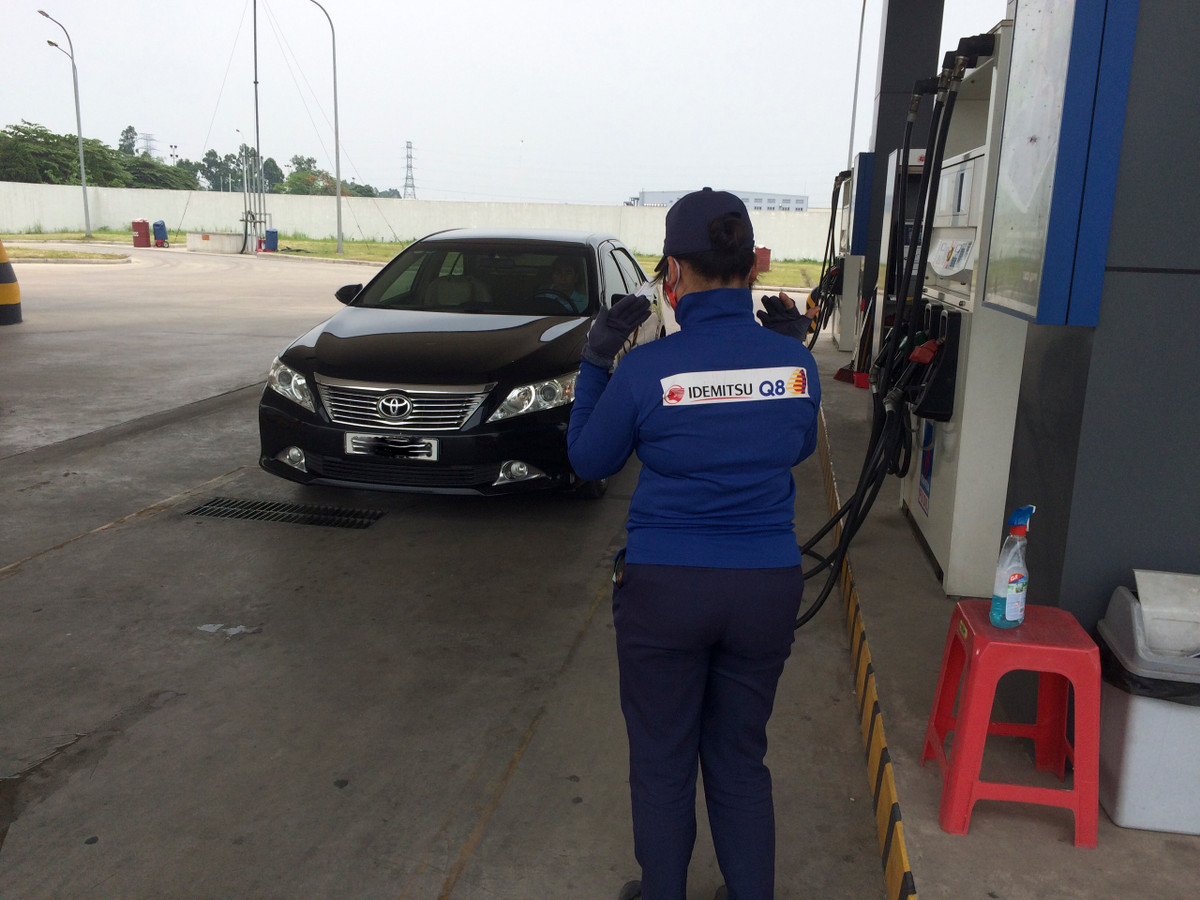 Nhân viên ra hiệu cho khách hàng điều khiển phương tiện vào đúng vị trí bơm xăng.