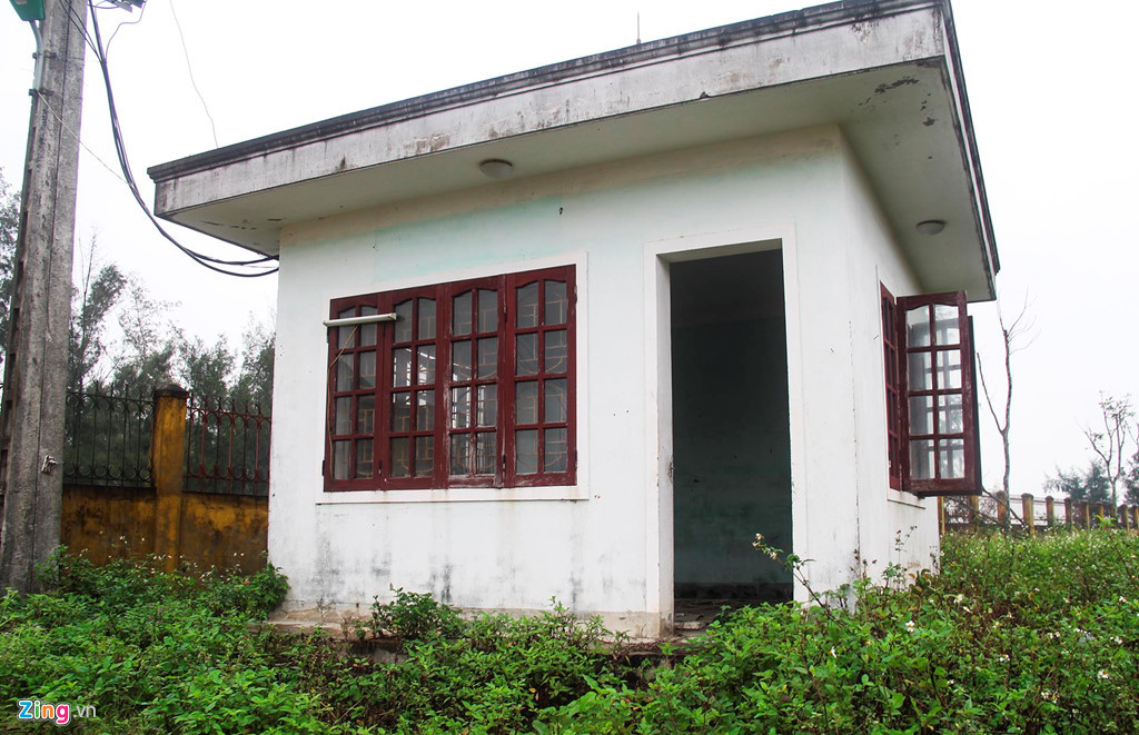 Phòng bảo vệ ngay cổng bị mất cửa, kính chắn gió bị vỡ, cỏ dại mọc vào quá bậc thềm, bên trong không có vật dụng nào ngoài bụi và rác.