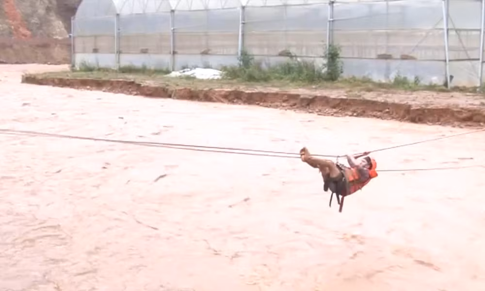 Để vượt qua dòng nước lũ đang chảy cuồn cuộn phía dưới, người dân phải mặc áo phao, treo mình lơ lửng, đu qua sông.