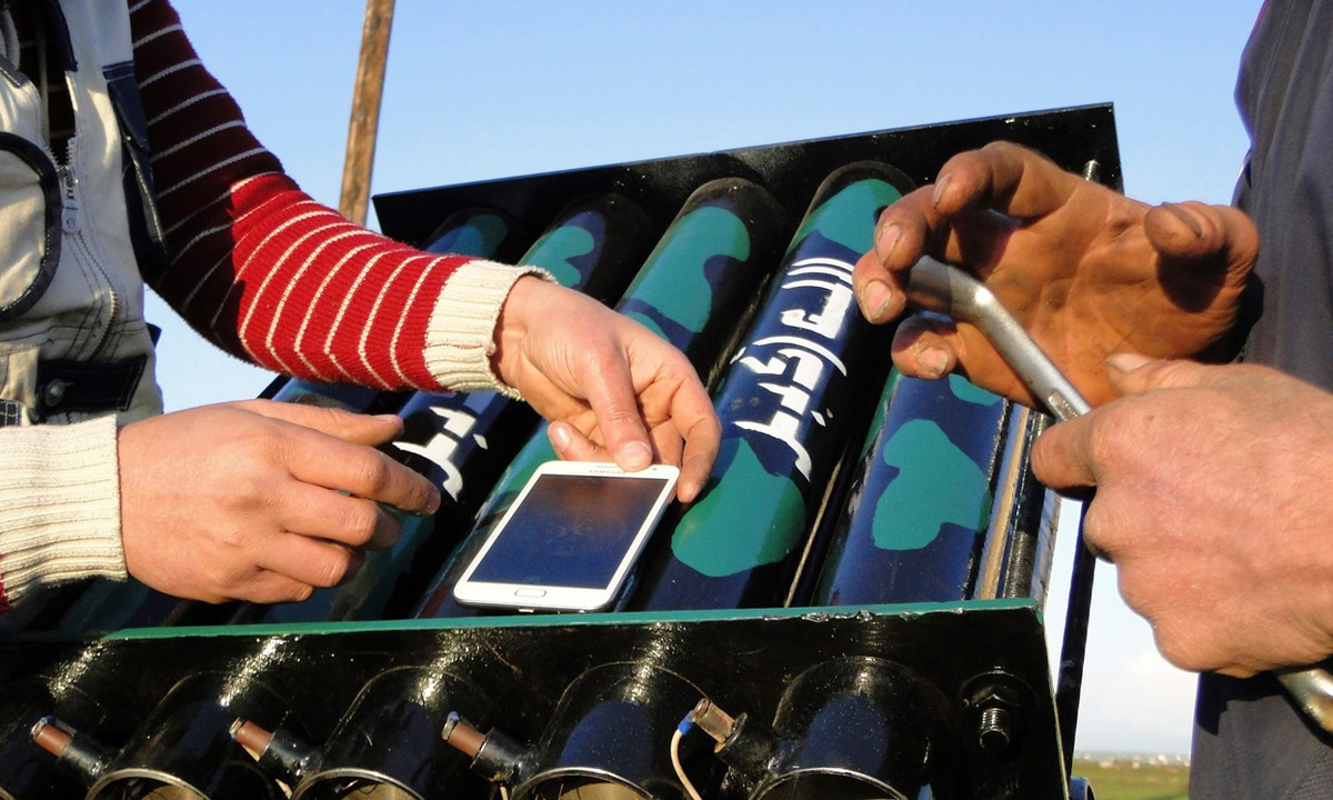 Ảnh: Các chiến binh Quân đội Syria tự do sử dụng la bàn điện tử trên điện thoại thông minh để giúp họ nhắm mục tiêu gần sân bay quân sự Menagh, Aleppo. Đó cũng là một dàn pháo phóng loạt tự chế.