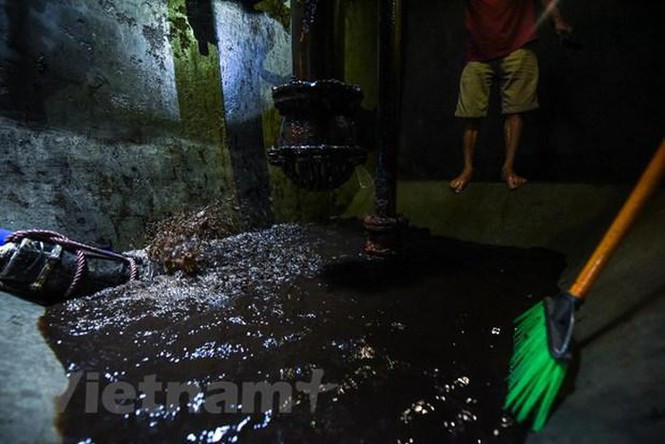 Do nước trong bể đang không đảm bảo, nên công ty buộc phải dùng máy bơm để hút hết nước trong bể ra, sau đó mới tiến hành thau rửa bể. (Ảnh: PV/Vietnam+)