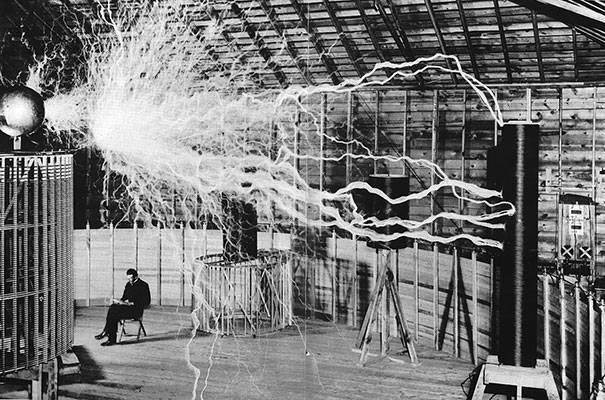 Nhà khoa học Nikola Tesla ngồi trong phòng thí nghiệm với phát minh bộ truyền khuếch đại.