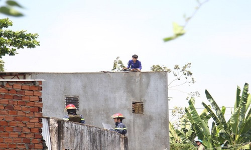 Nam thanh niên có biểu hiện như ngáo đá leo lên nóc nhà dân cố thủ. Ảnh: H.TÂM