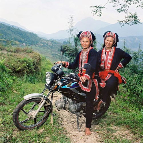 Hai chị em người Dao Đỏ trên chiếc xe máy nhãn hiệu Honda Win, phương tiện giao thông và chuyên chở chủ yếu của người dân vùng cao. Được đánh giá là phương tiện có động cơ khỏe và phù hợp với địa hình đồi núi nên Honda Win được hầu hết các gia đình vùng cao lựa chọn. Bức ảnh được chụp trong thời gian nghỉ ngơi của một gia đình Dao Đỏ, trước khi trở lại công việc hàng ngày.