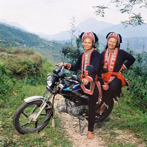Hai chị em người Dao Đỏ trên chiếc xe máy nhãn hiệu Honda Win, phương tiện giao thông và chuyên chở chủ yếu của người dân vùng cao. Được đánh giá là phương tiện có động cơ khỏe và phù hợp với địa hình đồi núi nên Honda Win được hầu hết các gia đình vùng cao lựa chọn. Bức ảnh được chụp trong thời gian nghỉ ngơi của một gia đình Dao Đỏ, trước khi trở lại công việc hàng ngày.
