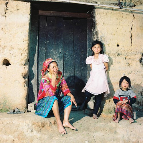 Một gia đình người Mông trước cửa nhà. Ngôi nhà đơn sơ với tường được đắp bằng đất vẫn là kiểu nhà phổ biến cửa người Mông tại các tỉnh vùng núi phía Bắc (Nhà trình tường). Bức ảnh được chụp tại một bản nhỏ gần thị trấn Vinh Quang - Hoàng Su Phì.