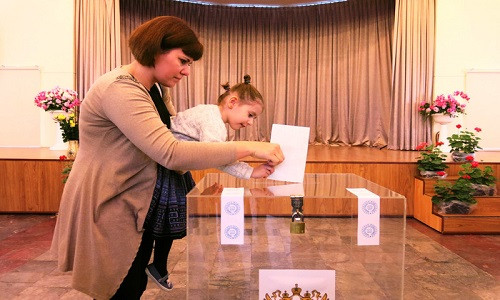 Sau khi điền đầy đủ thông tin trong phiếu bầu, cử tri sẽ bỏ phiếu vào một thùng phiếu được niêm phong và khóa cẩn thận. Trong ảnh, người mẹ hướng dẫn con gái bỏ phiếu bầu vào thùng kiểm phiếu ở Hà Nội