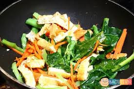 Tiếp đó, cho đậu đã rán vào chảo rau muống, tiếp tục xào đều đến khi rau muống chín vừa tới, rau ăn hơi giòn, không chát và không quá nhũn là được.