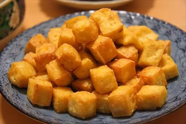 Đậu phụ cắt thành từng miếng vuông hoặc hình chữ nhật rồi rán vàng đều.